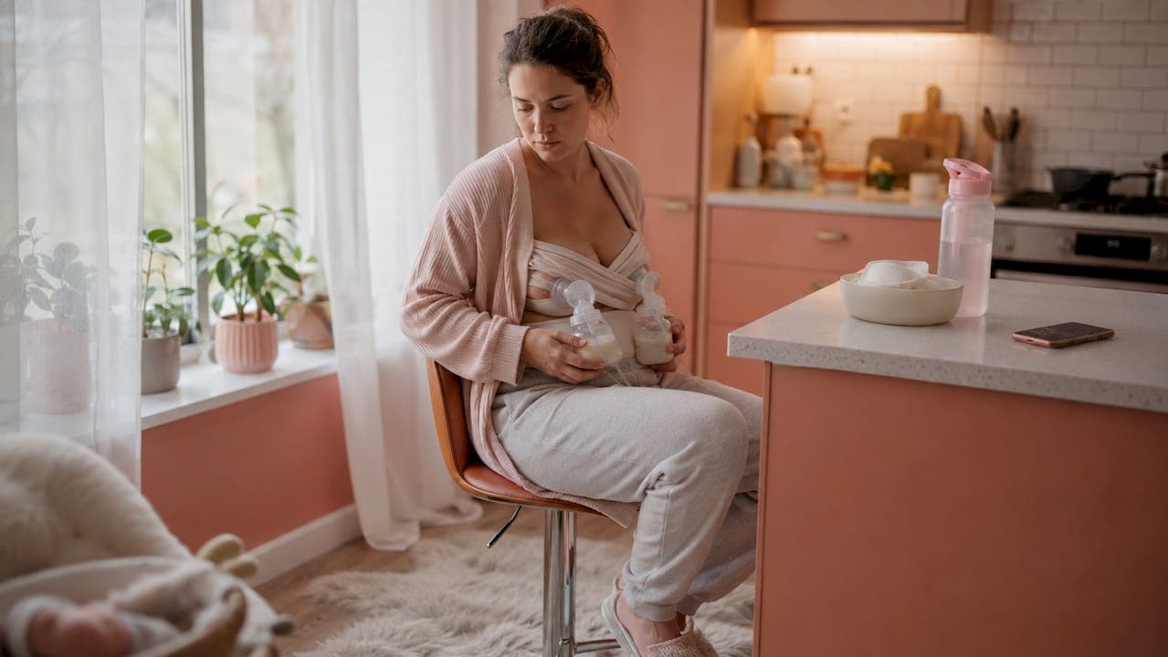 Twin mom pumping breast milk at home nursery