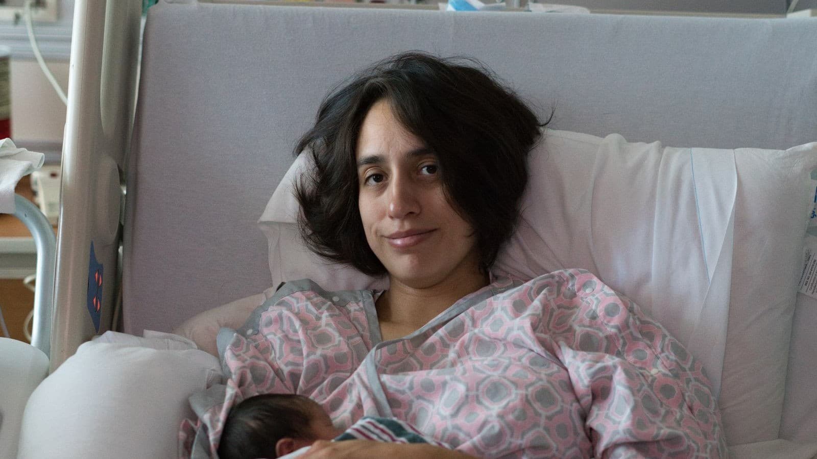 New mother resting in a hospital bed while holding her newborn