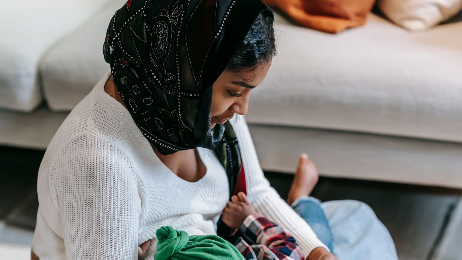 Mother checking her phone while holding her baby at home